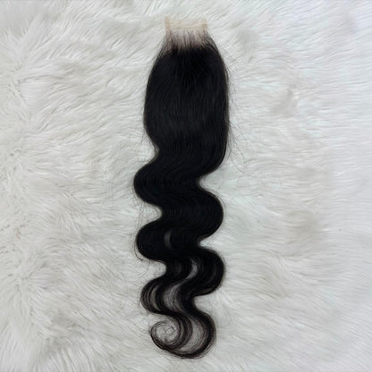 A single 2x6 HD lace closure  black body wave  with a natural-looking light beige lace base, laid flat on a white faux fur background.